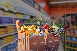 Shopping cart filled with groceries in a blurred grocery store aisle.